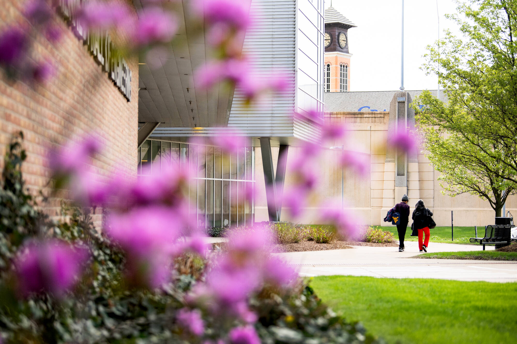 Kennedy hall with students walking by and pretty flowers in the forefront